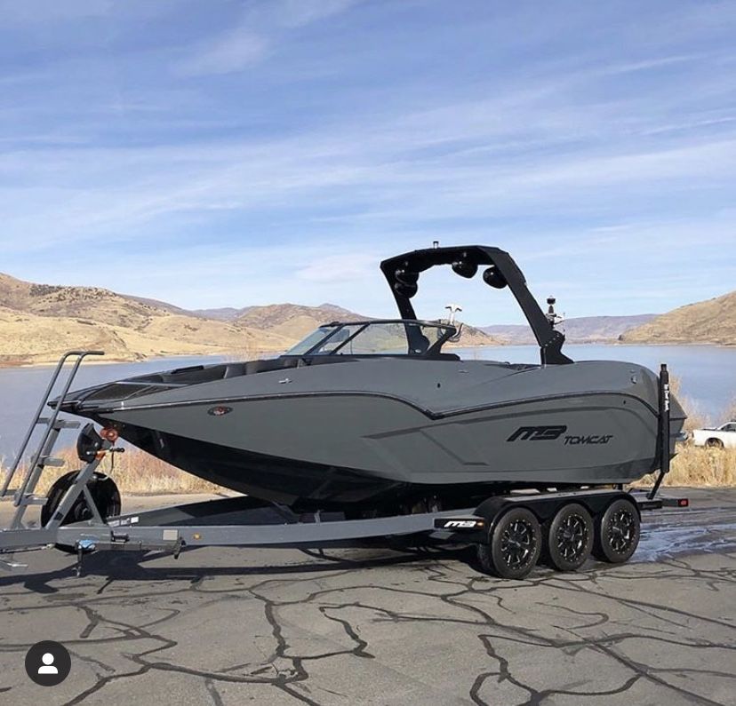 Wake boat on a triple-axle trailer near the water